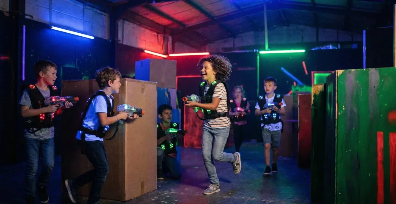 Groupe d'enfants de 7-10 ans en pleine session de Laser Game dans une salle aux néons colorés, expressions de concentration et d'amusement